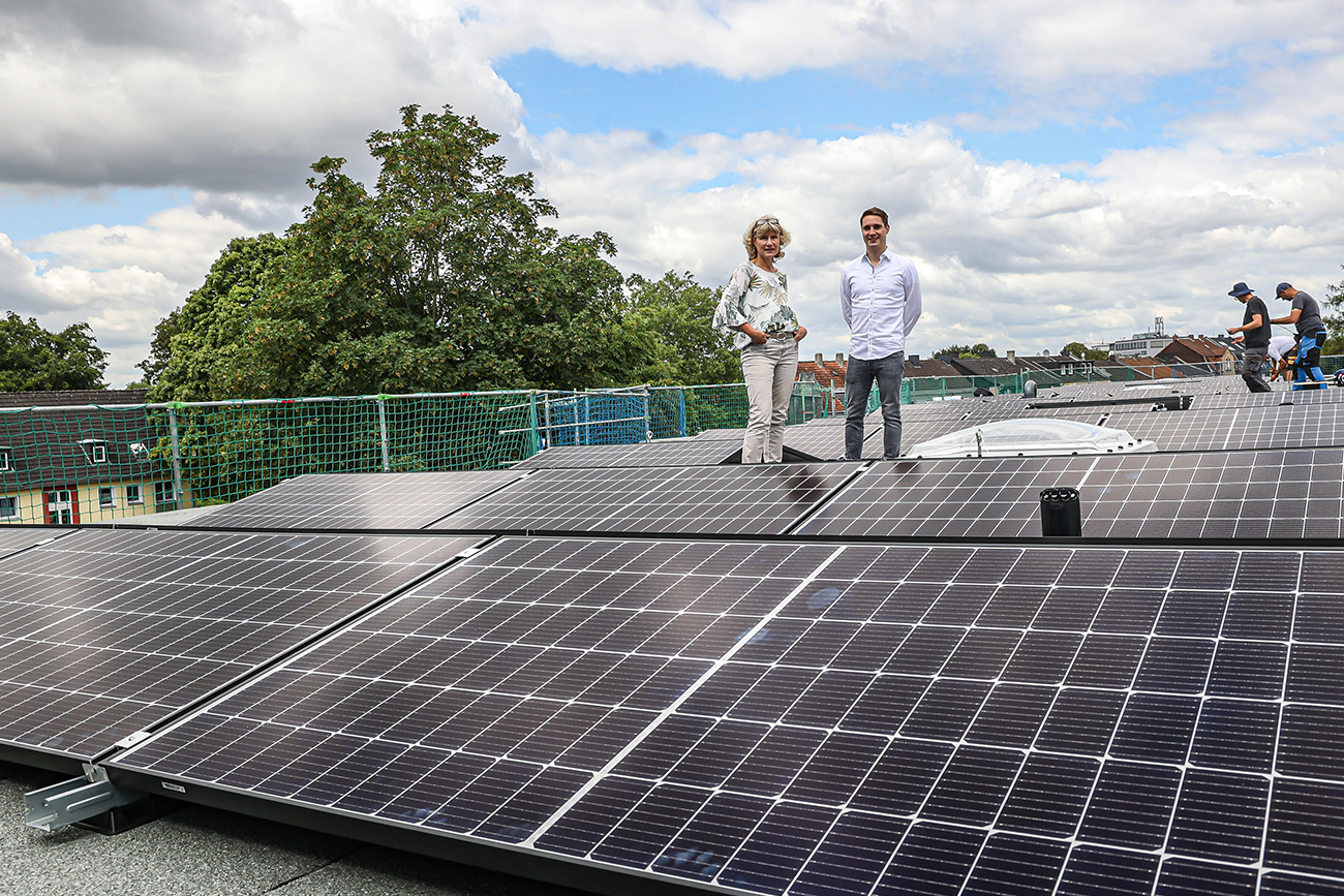 Zwei DOGEWI21-Mitarbeitende auf dem Dach inmitten der neuen Fotovoltaikanlagen.