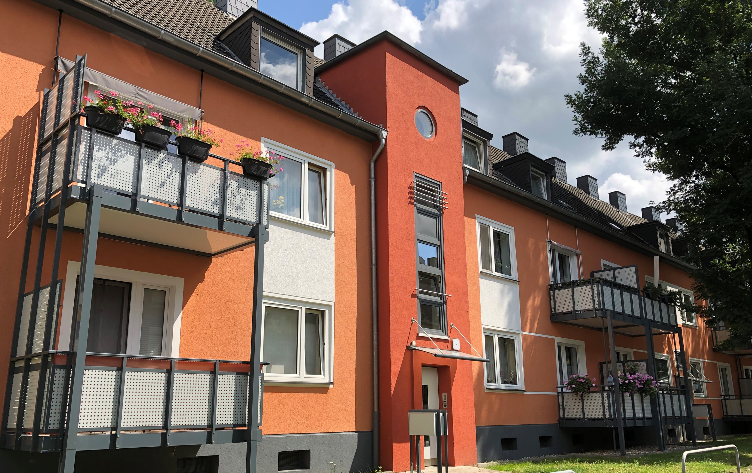 Modernes, rot gestrichenes Mehrfamilienhaus mit Balkonen.