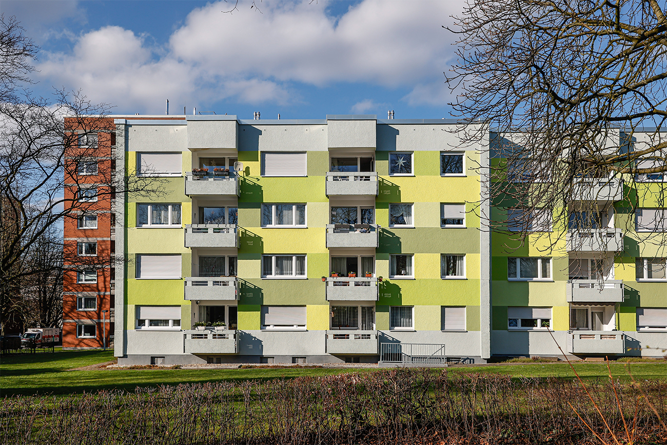 Gelbes Mehrfamilienhaus mit modernen Balkonen.
