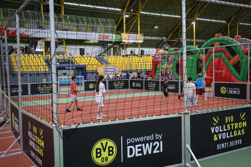 Kinder die in einer Halle Fußball spielen.