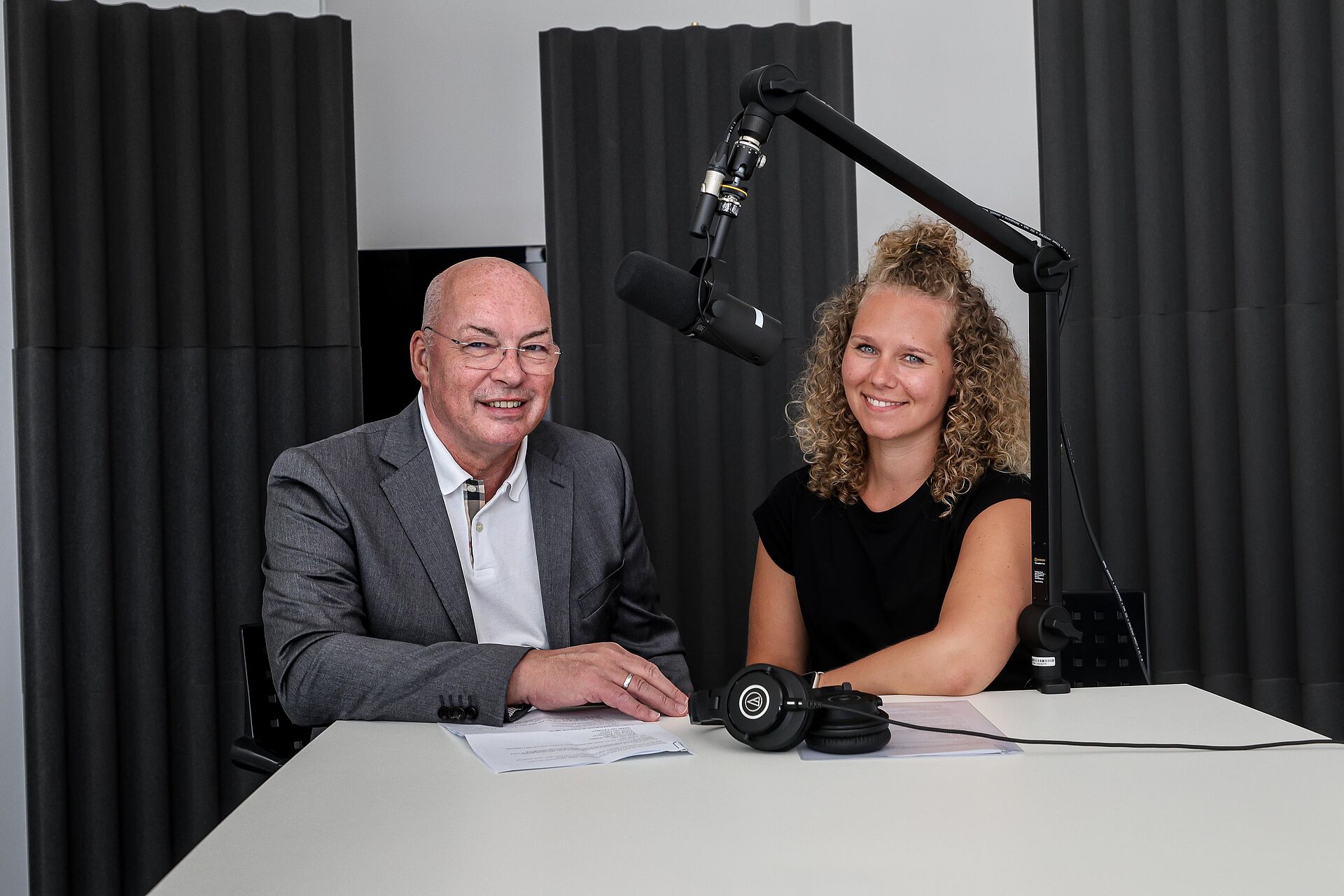 Klaus Graniki und Helen Waltener von DOGEWO21 sitzen an einem Tisch mit Aufnahmemikrofon