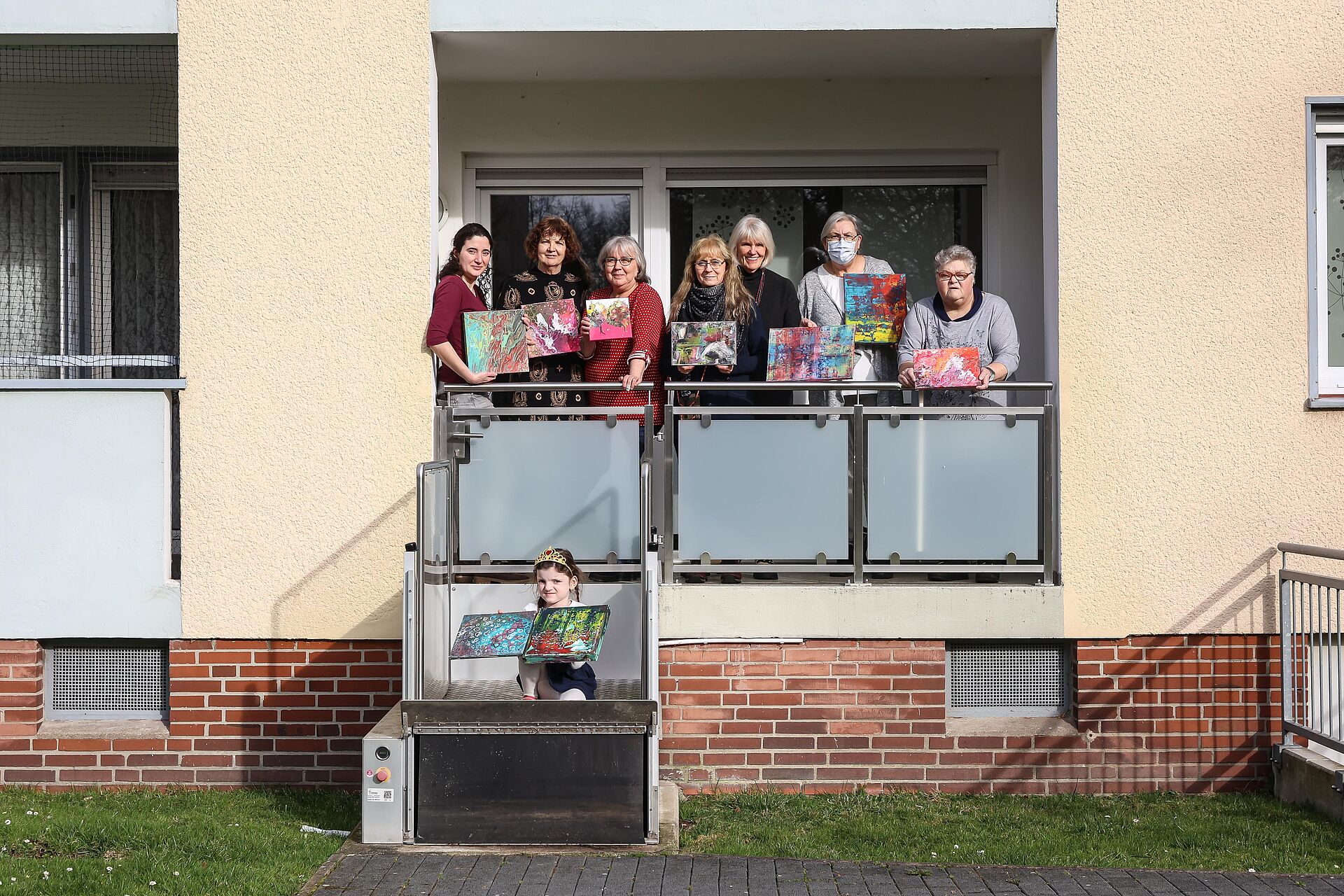 Mehrere Frauen zeigen ihre selbstgemalten Bilder auf dem Balkon des Mietertreffs Kuh31