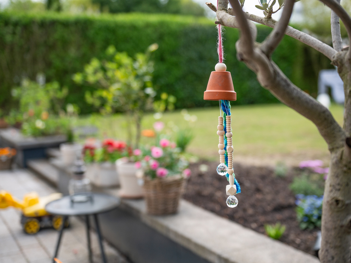 Eine Terrasse mit Stühlen und im Vordergrund ein Windspiel im Baum. 