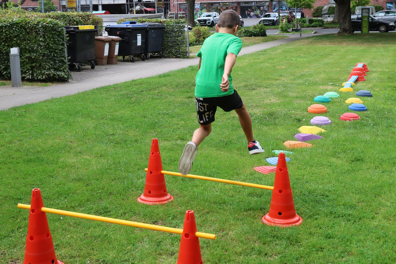 Ein Kind springt über einen Hindernisparcours auf einer grünen Wiese