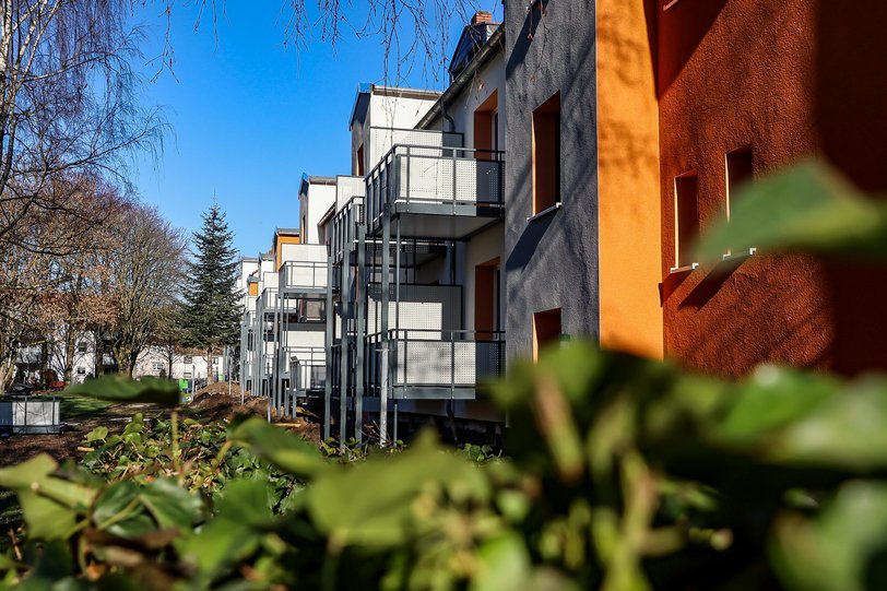 Modernisierte Hausrückwände von Mehrfamilienhäusern mit bunter Farbe und neuen Balkonen und Blick ins Grüne