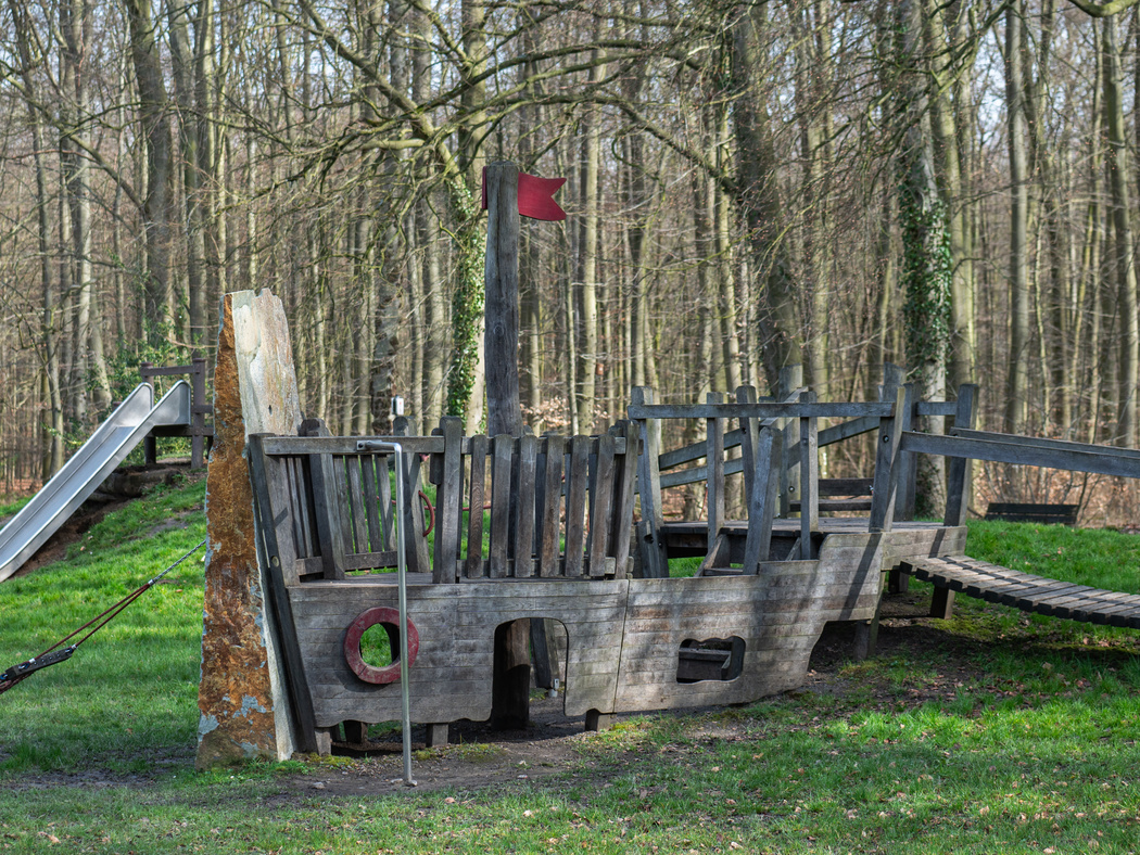 Ein Klettergerüst aus Holz im Wald, was aussieht wie ein Boot.