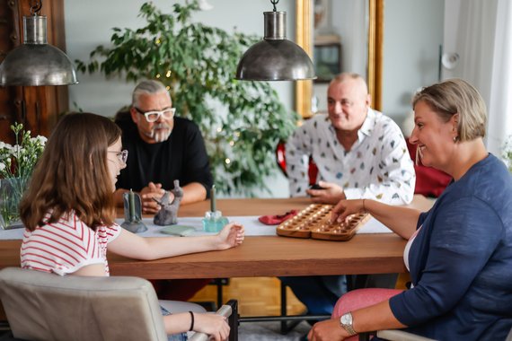 Eine Familie sitzt gemeinsam lachend um einen Tisch