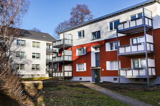 Frisch sanierte Mehrfamilienhäuser, z. T. mit neu aufgestockten Etagen inmitten von Grün und winterlichem Geäst.