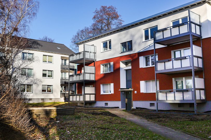 Frisch sanierte Mehrfamilienhäuser, z. T. mit neu aufgestockten Etagen inmitten von Grün und winterlichem Geäst.