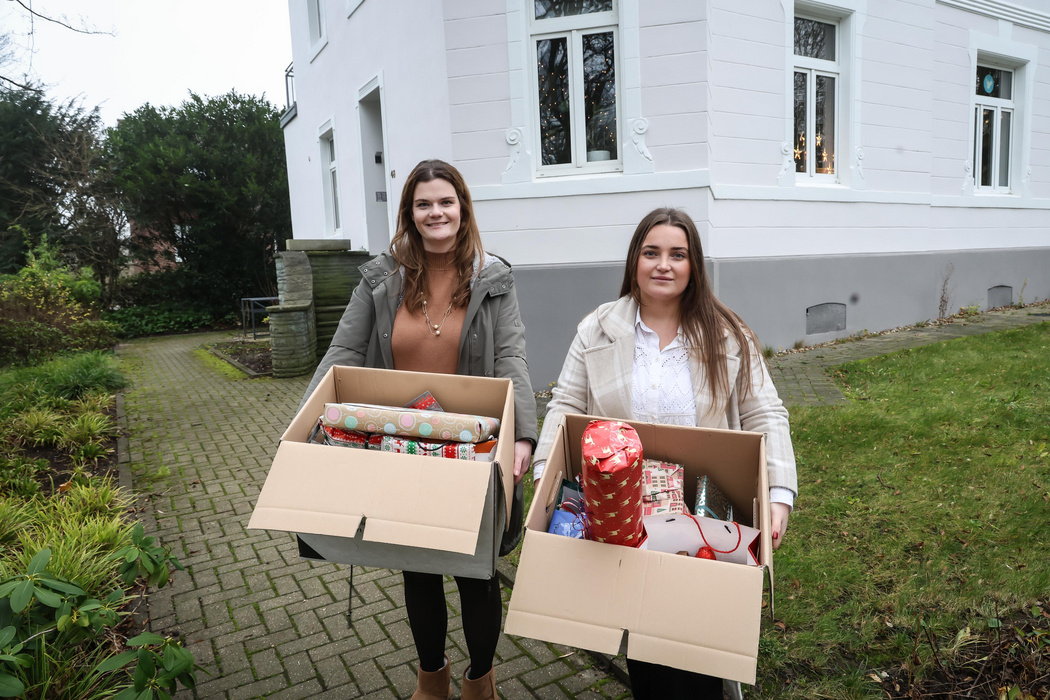 Zwei Frauen mit Geschenken in einer Box vor einer alten Stadtvilla