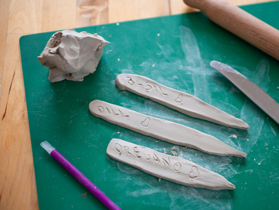 Gebastelte Ton-Kräuter-Stecker auf einer grünen Matte