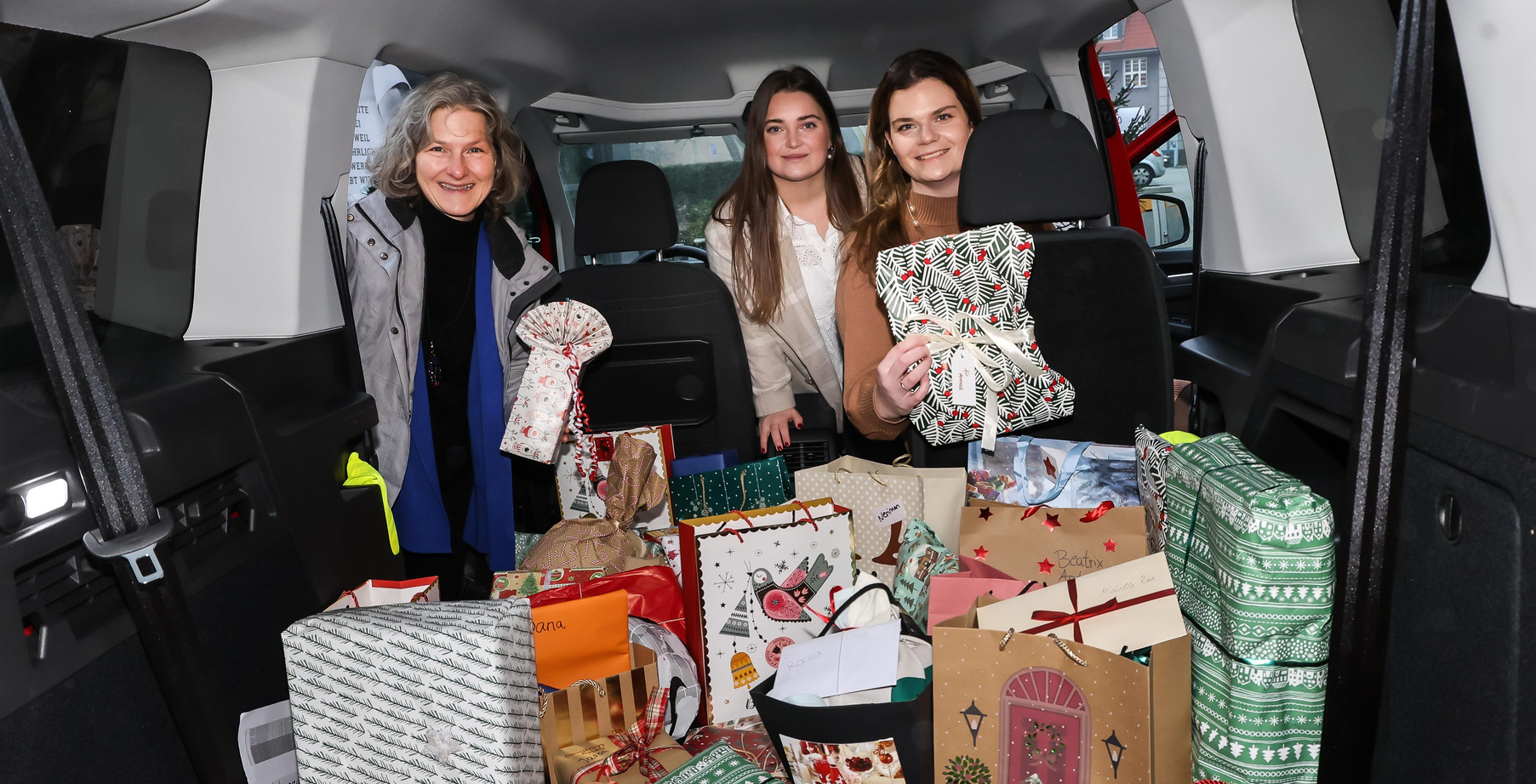 Drei Frauen in einem Caddy voller bunter Geschenke