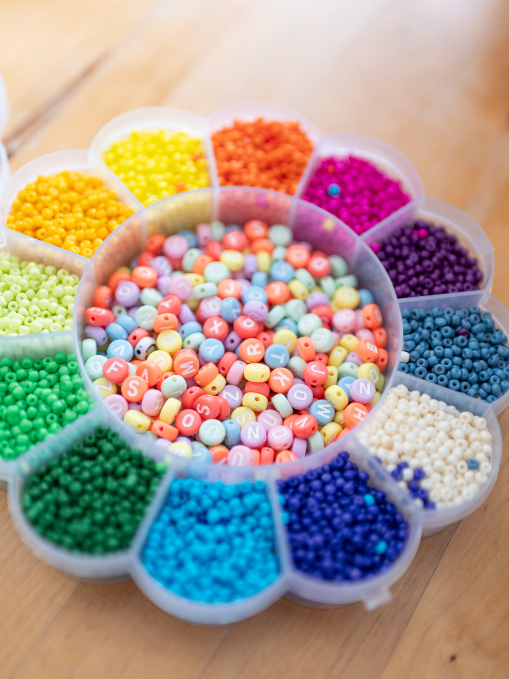 Eine Schachtel mit vielen kleinen Fächern, in die bunte Perlen einsortiert sind. Die Schachtel sieht wie eine Blume aus.
