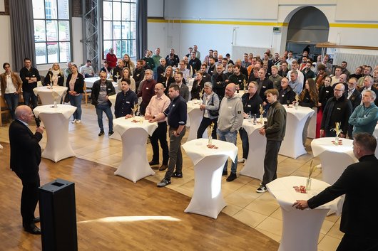 Menschen bei einer Rede hinter weißen Stehtischen