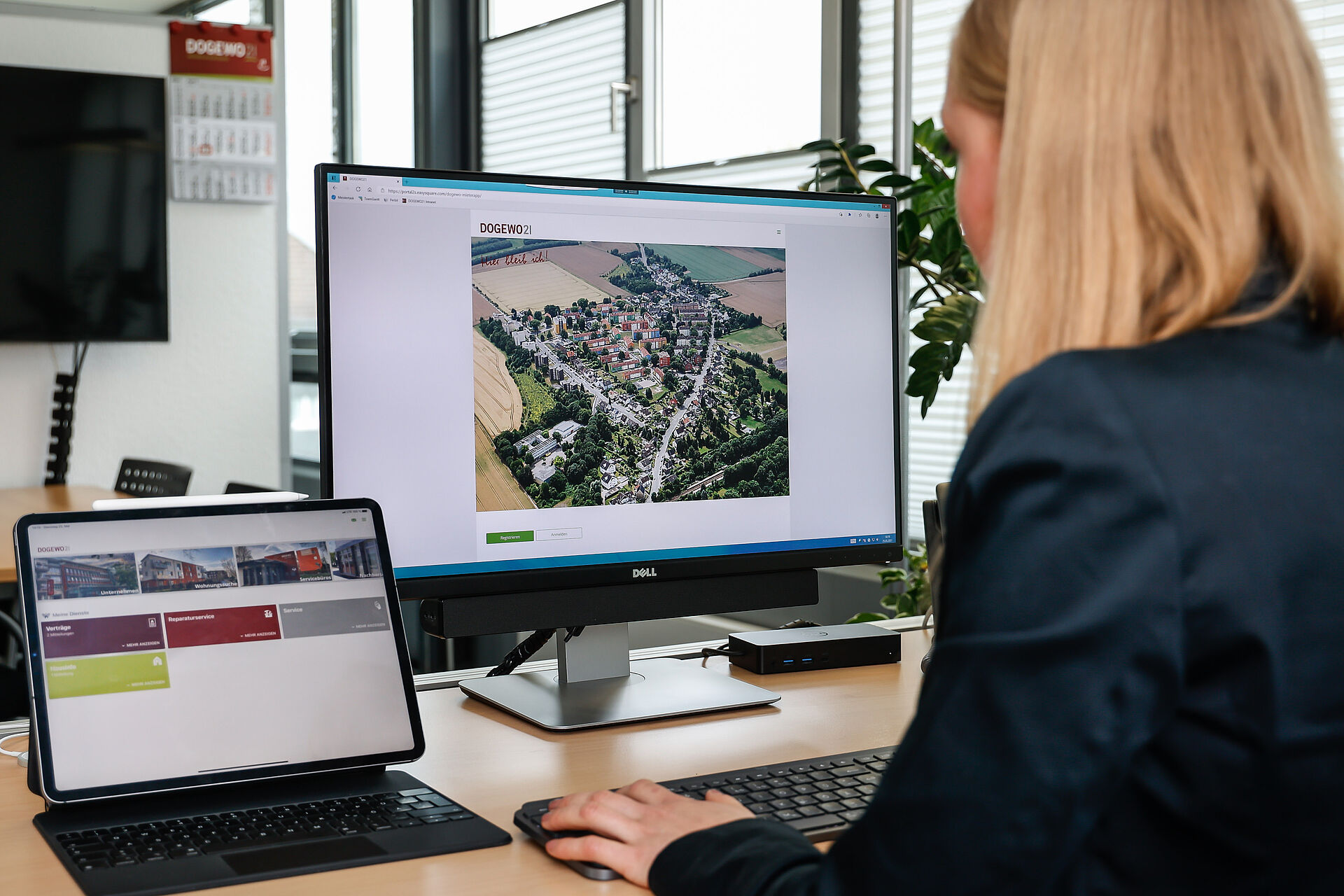 Eine Frau schaut auf einen Computermonitor und einen iPad-Bildschirm, der das DOGEWO21-Mieterportal zeigt