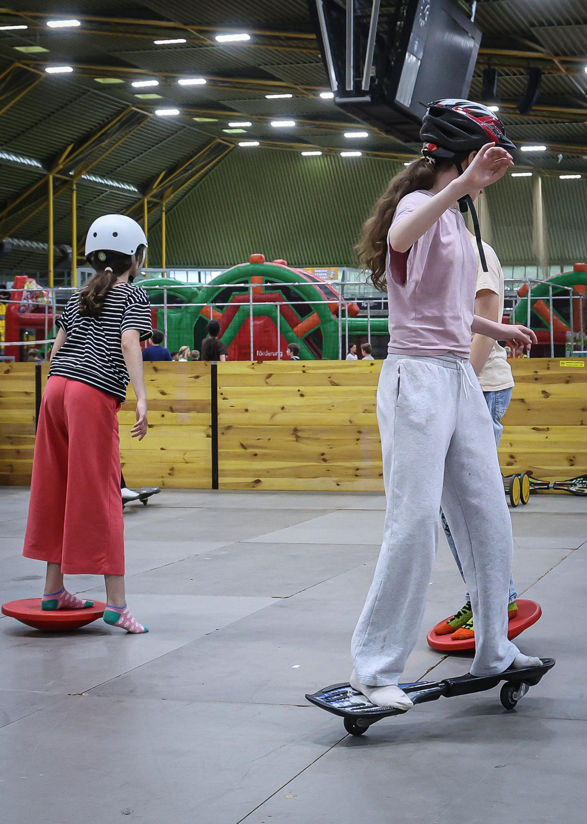Drei Kinder die Skateboard fahren und auf einem Balance-Board balancieren.