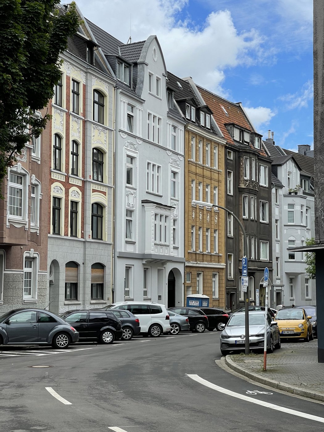 Straßenzug zum parkenden Autos und alten Mehrfamilienhäusern