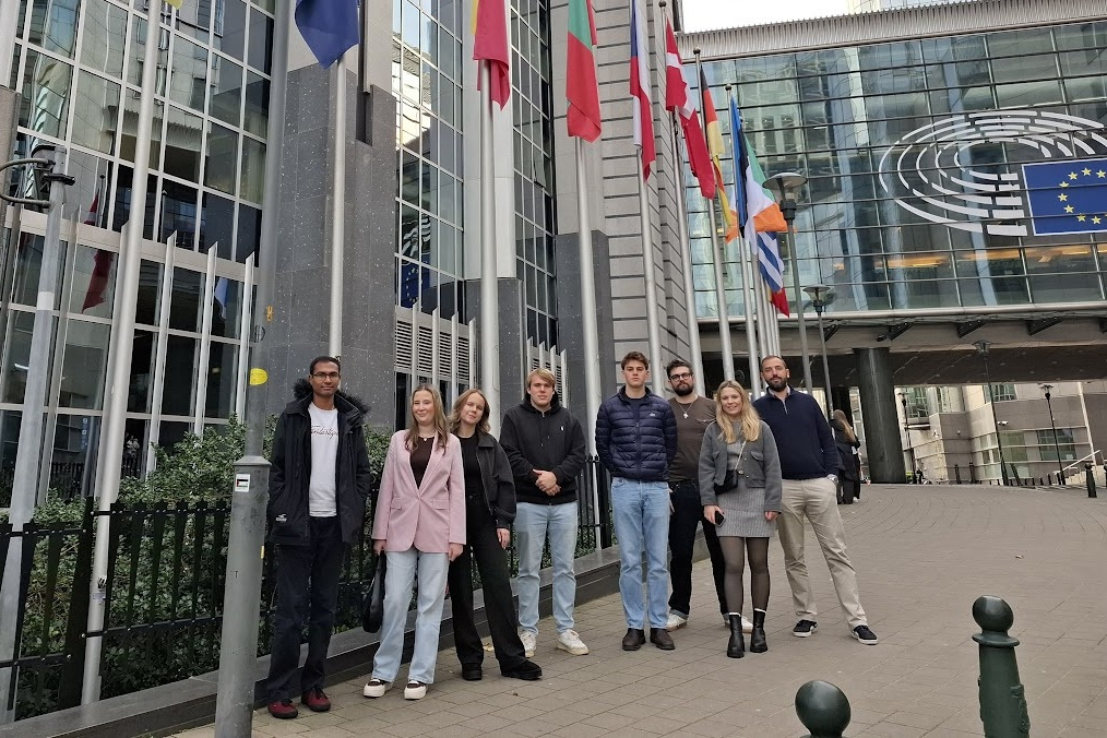 Mehrere junge Menschen stehen vor einem Gebäude der europäischen Regierung.