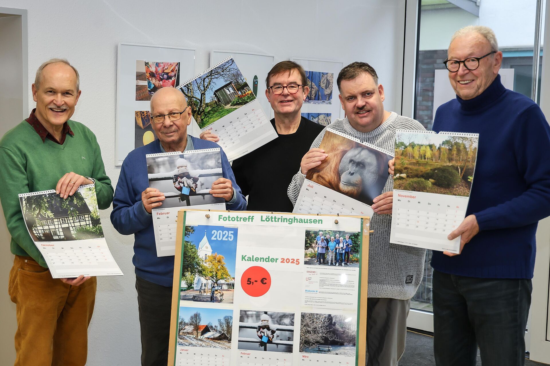 Fünf Männer präsentieren die Fotomotive ihres neuen Kalenders in einem Nachbarschaftstreffpunkt von DOGEWO21.