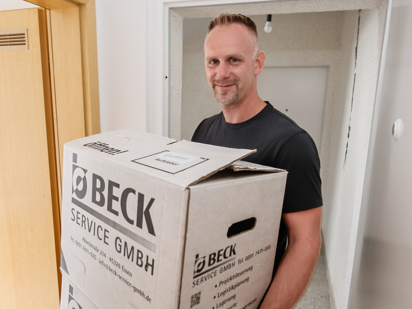Ein Mann trägt zwei Umzugskisten