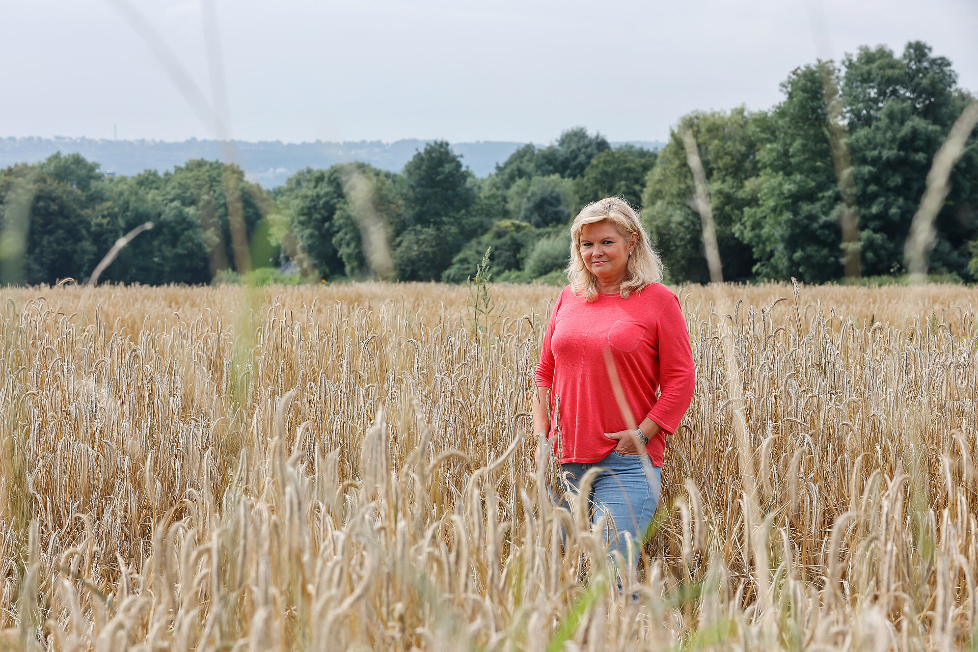 Eine Frau mit rotem Oberteil steht in einem Kornfeld