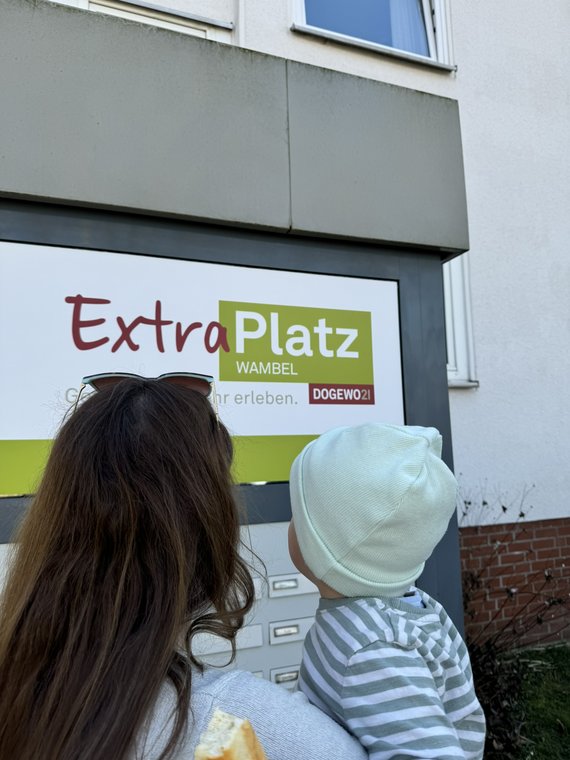Mutter mit Kind auf dem Arm vor dem Eingang ExtraPlatz