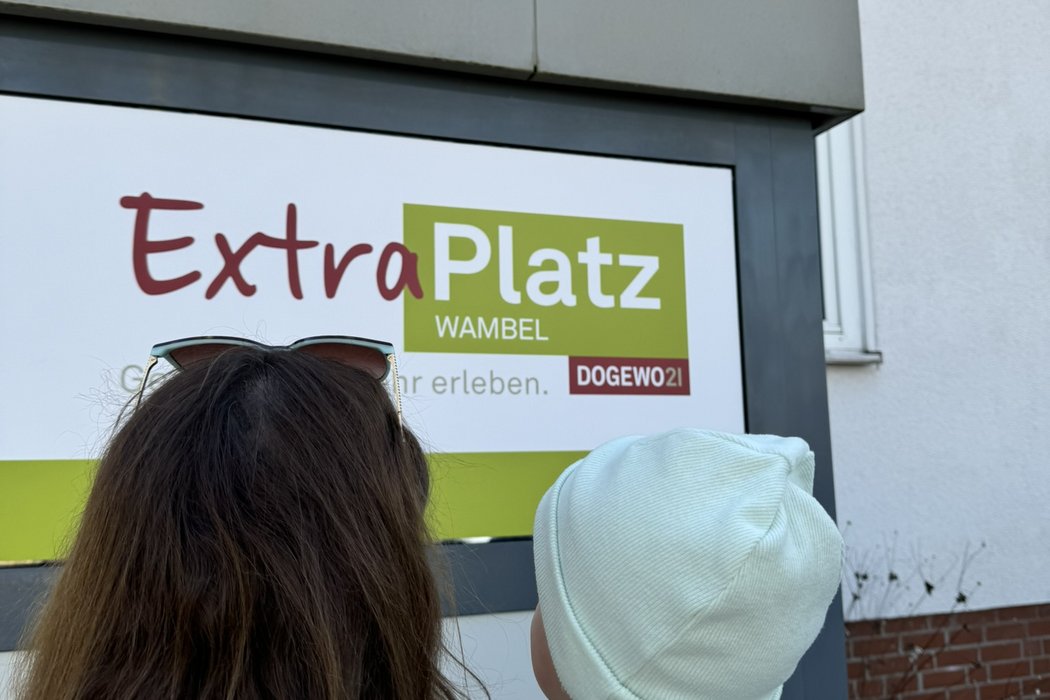 Mutter mit Kind auf dem Arm vor dem Eingang ExtraPlatz