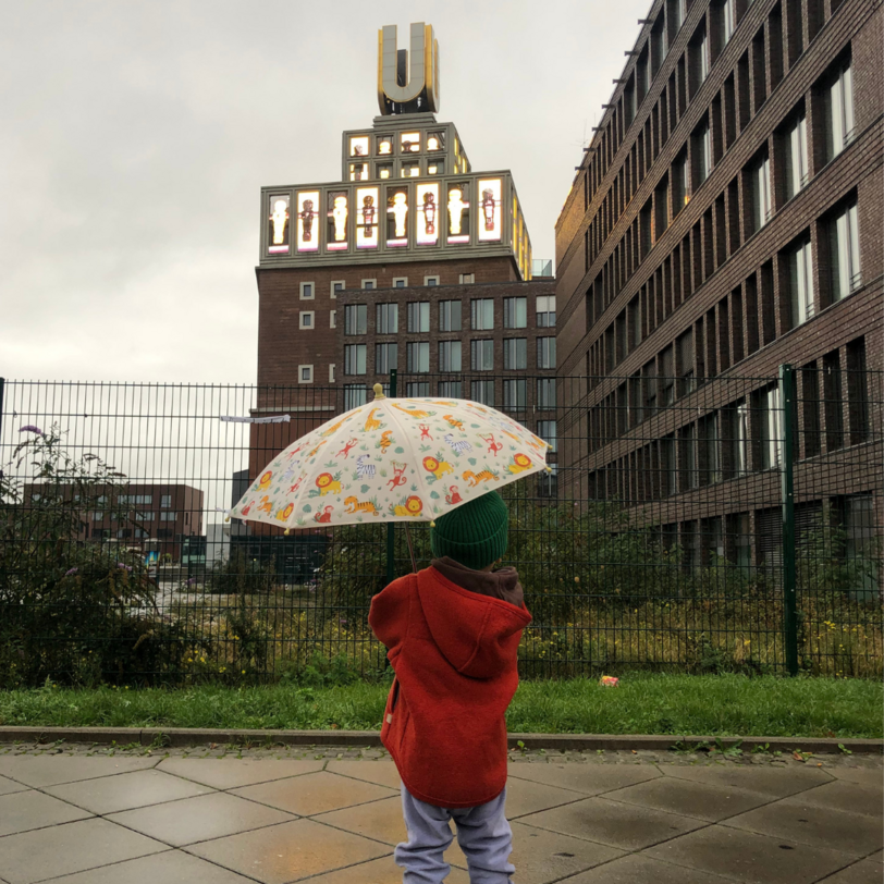 Kind mit Regenschirm schaut zum U-Turm