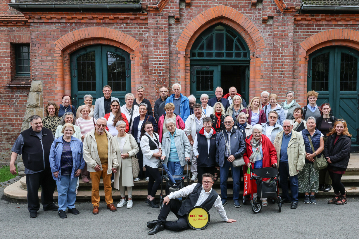 Männer und Frauen stehen vor dem historischen Eingang einer ehemaligen Zeche.