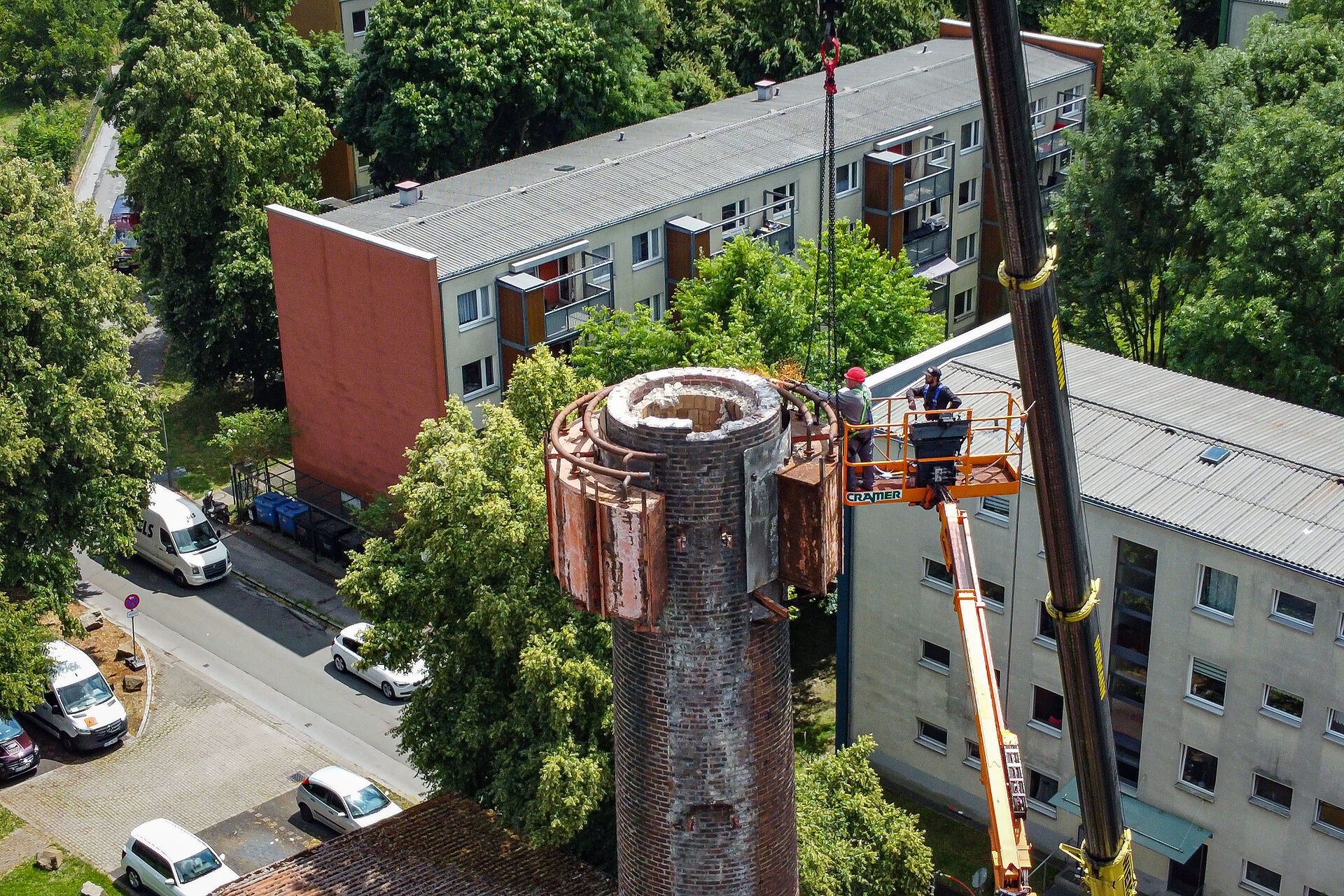 Zwei Männer entfernen von einer Hebebühne aus die Wassertanks an einem Schornstein in 30 Metern Höhe