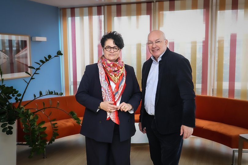 Im in hellblau und orangenen Farbtönen gehaltenen Foyer des Seniorenwohnhauses Sonnenhof stehen die Geschäftsführerin der SHDO und der DOGEWO21-Geschäftsführer und schauen lächelnd in die Kamera des Fotografen.