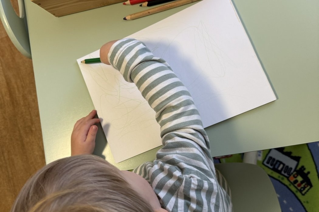 Kind malt mit Bundstiften auf ein Blattpapier