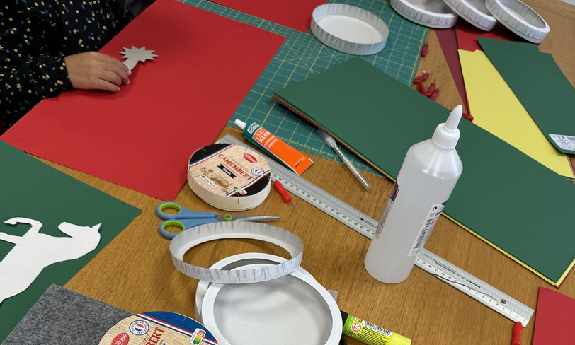 Auf einem Tisch liegen Bastelmaterialien wie Kleber, Pappe und Tonpapier.