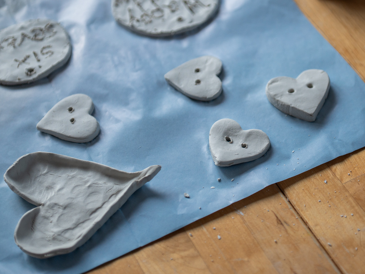 Sieben verschiedene Tonherzen die auf dem Tisch zum trocknen liegen.