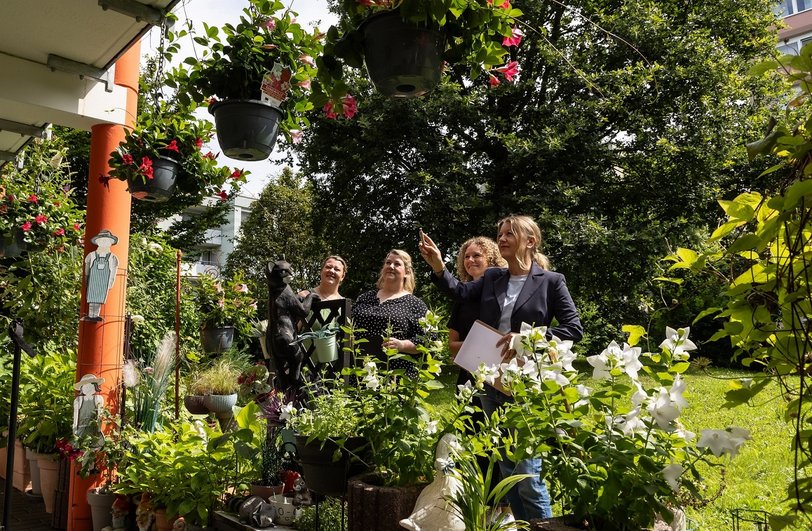 4 Frauen schauen sich die Blütenpracht an Balkonen an.