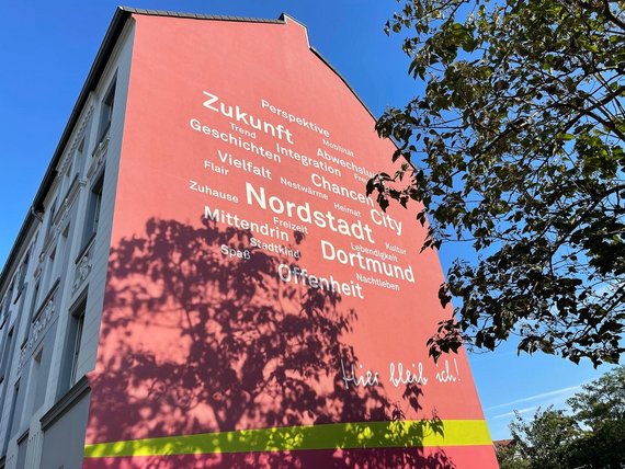 Seitenansicht von einem Mehrfamilienhaus mit Schriftzug