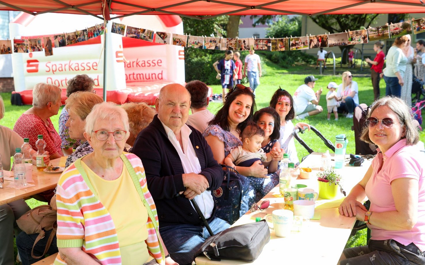 Personen bei einem Sommerfest auf einer Bierzeltgarnitur