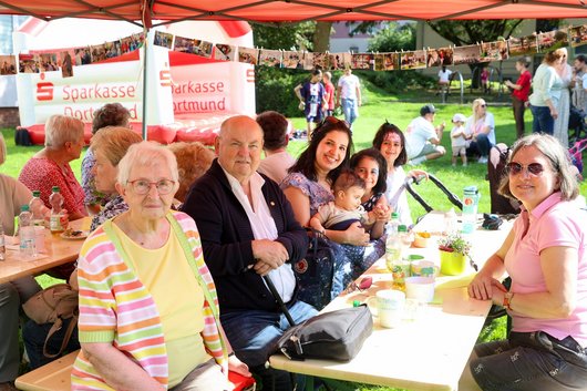 Mehrere Menschen sitzen beim Sommerfest an Bierzeltgarnituren