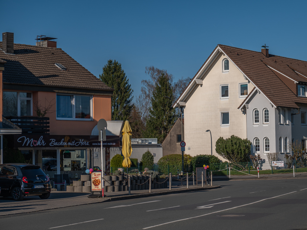 Blick über eine Straße auf eine Bäckerei und Wohnhäuser