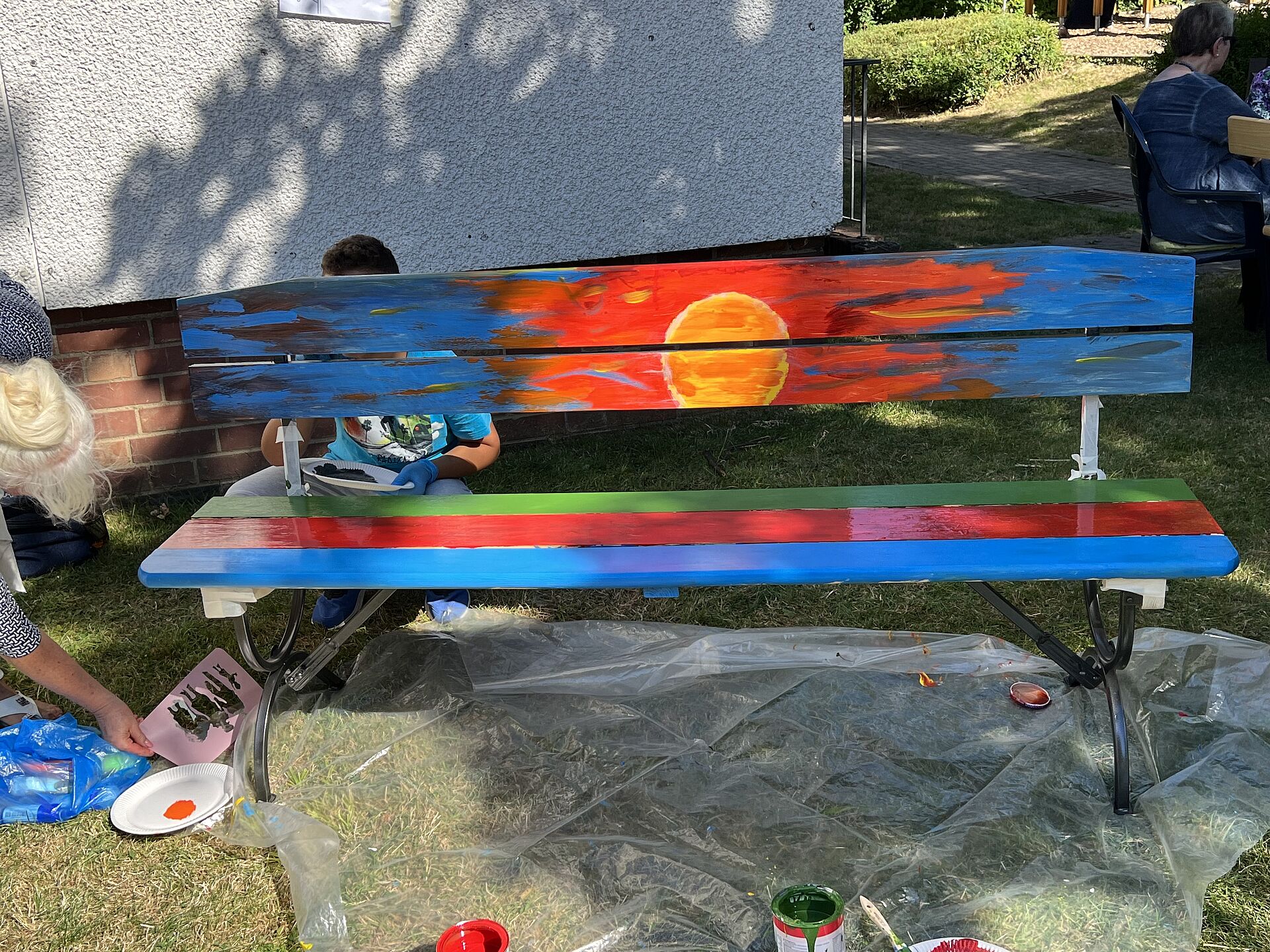 Eine bunt bemalte Bank steht im Garten der Nachbarschaftsagentur Wambel