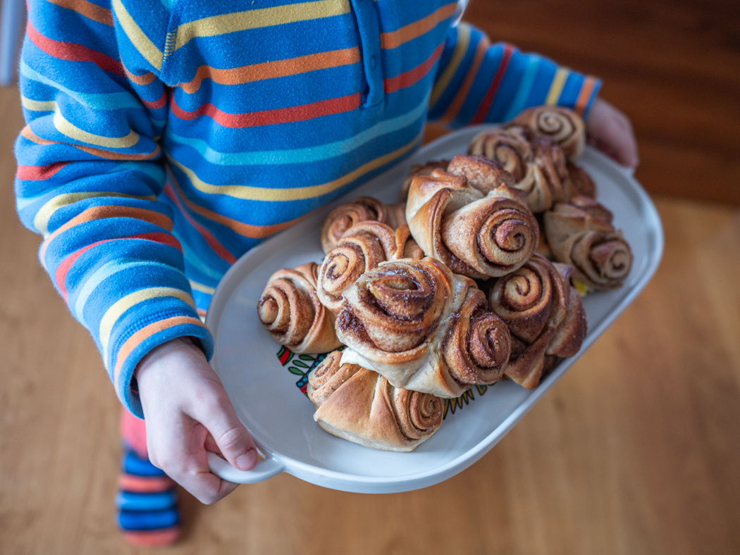 Ein Kind trägt ein Tablett mit Zimtschnecken