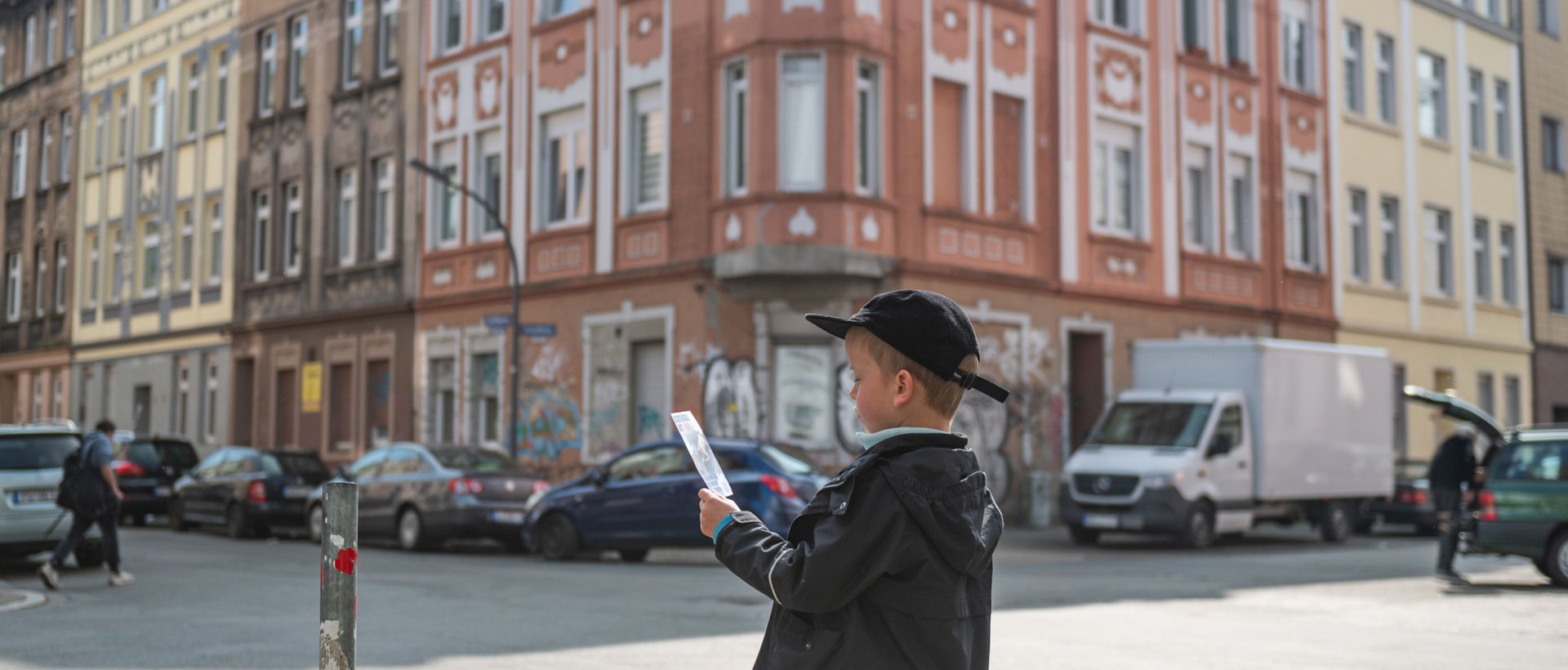 Kind an einer Straßenkreuzung mit einem Flyer