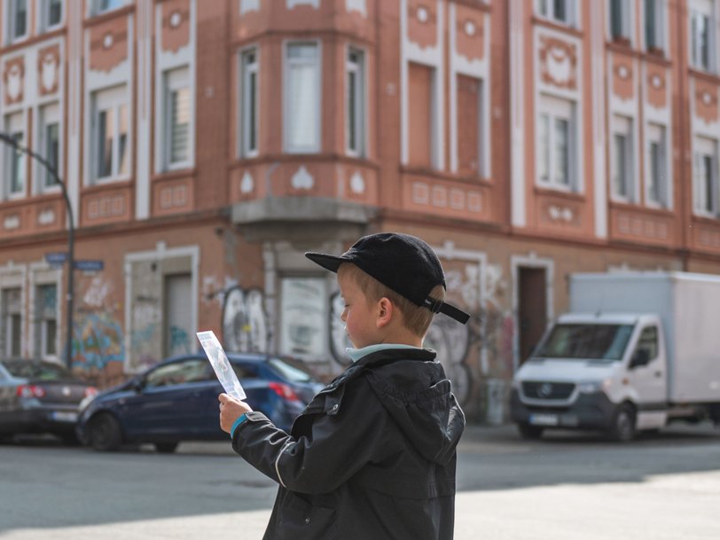 Kind an einer Straßenkreuzung mit einem Flyer