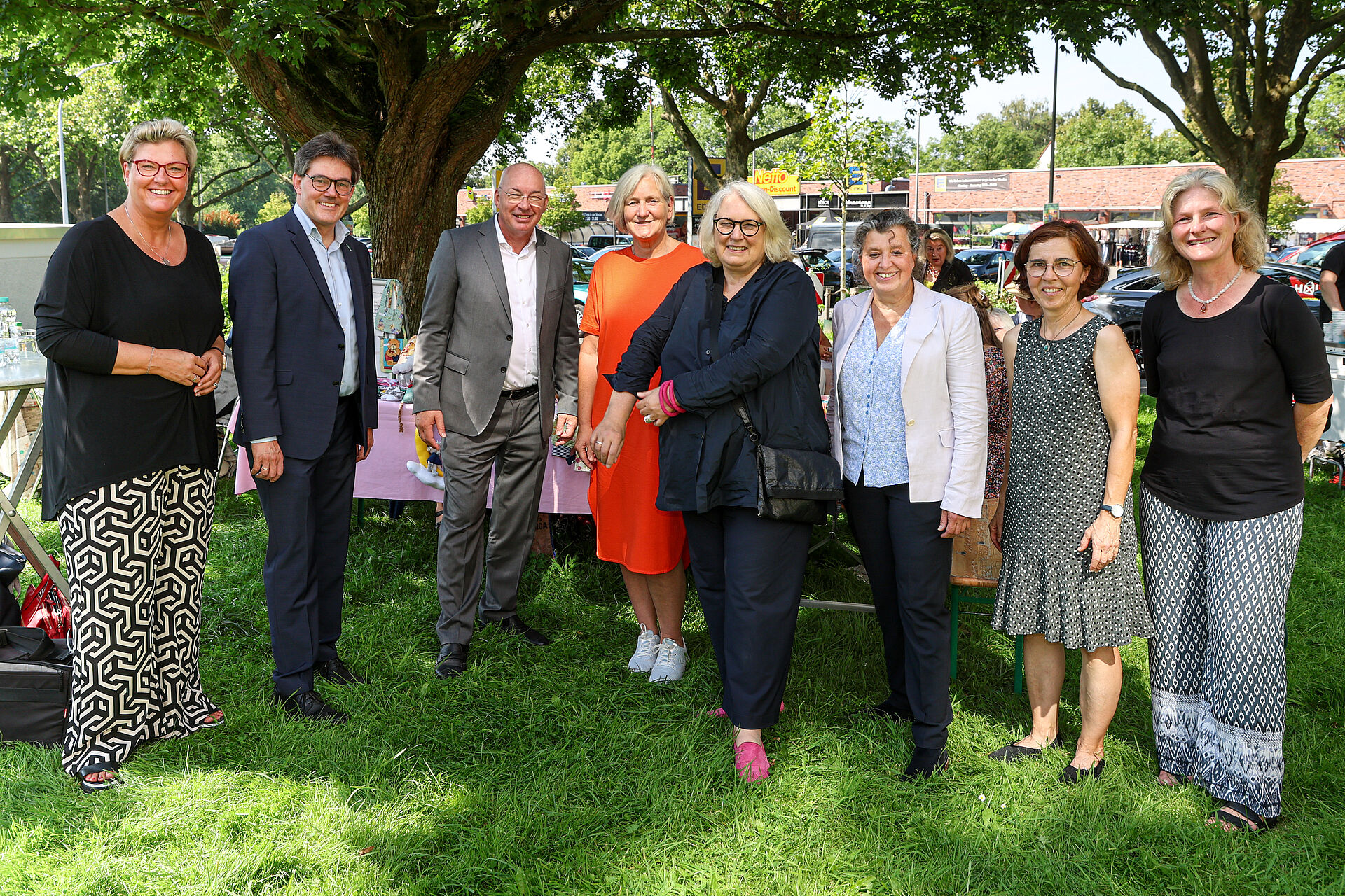 Geschäftsführung von DOGEWO21 und Diakonie stehen mit Mitarbeiterinnen, unter anderem der Nachbarschaftsagenturen für ein Foto im Garten zusammen