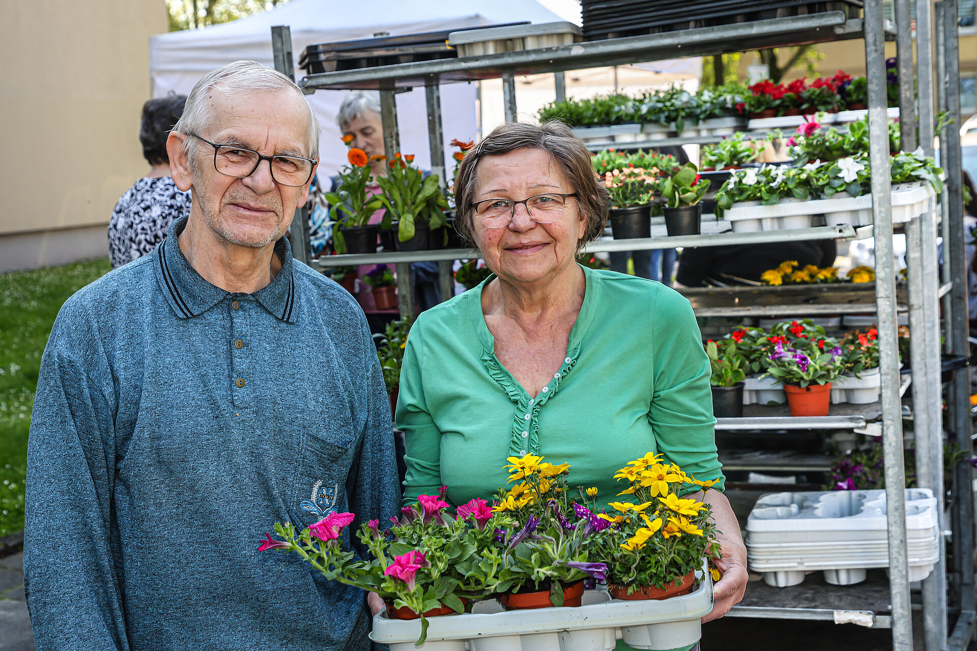 Mann und Frau mit Blumen lächeln in die Kamera