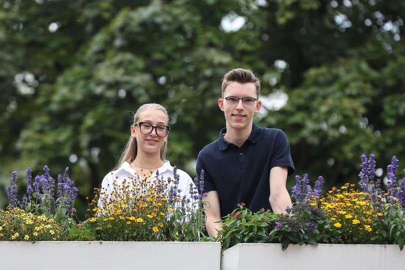 2 Azubis vor einer Blumenreihe