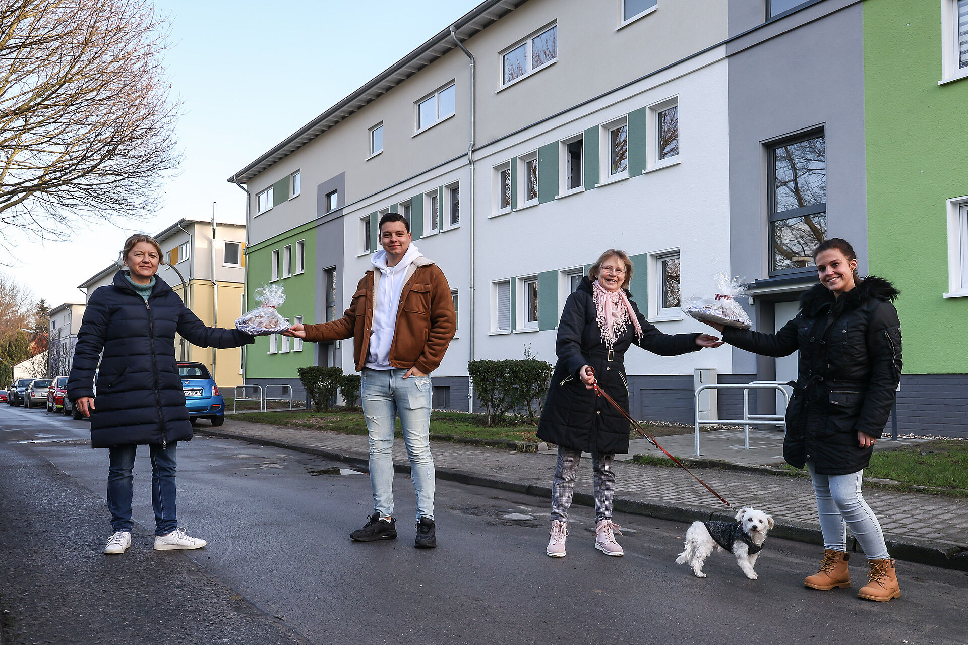 Menschen stehen vor Wohnhäusern und überreichen das traditionelle Brot und Salz zum Einzug