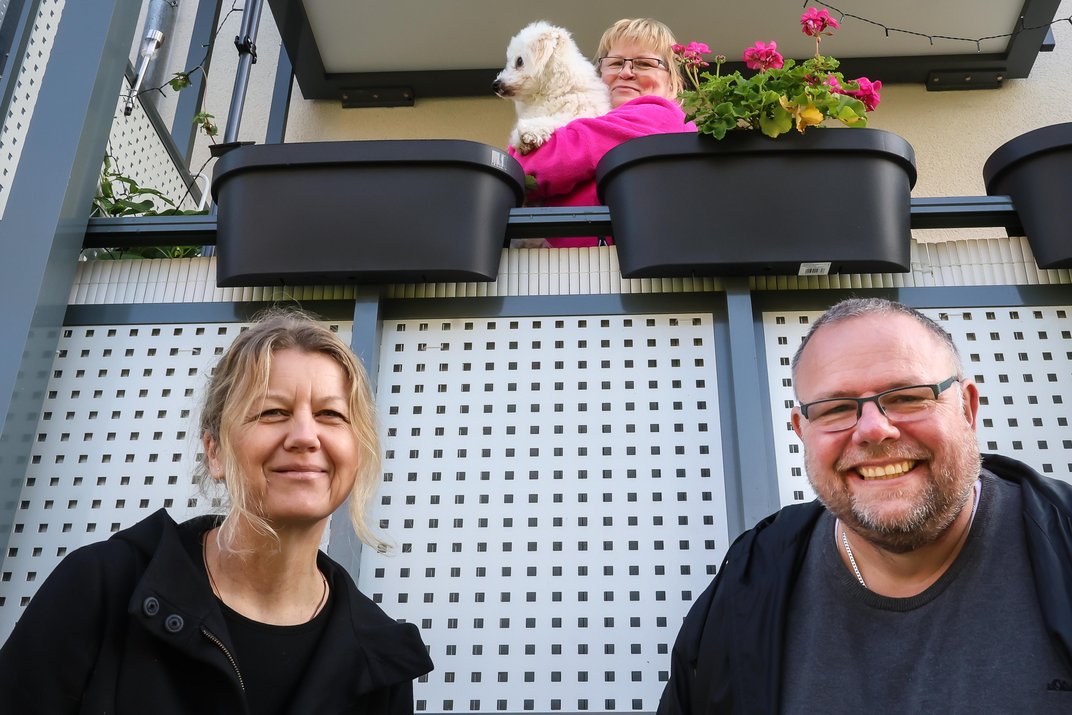 Tanja Meier (DOGEWO21, l.) und Tim Haverkamp (DOGEWO21, r) freuen sich mit Mieterin Regina vor Ihrem Balkon