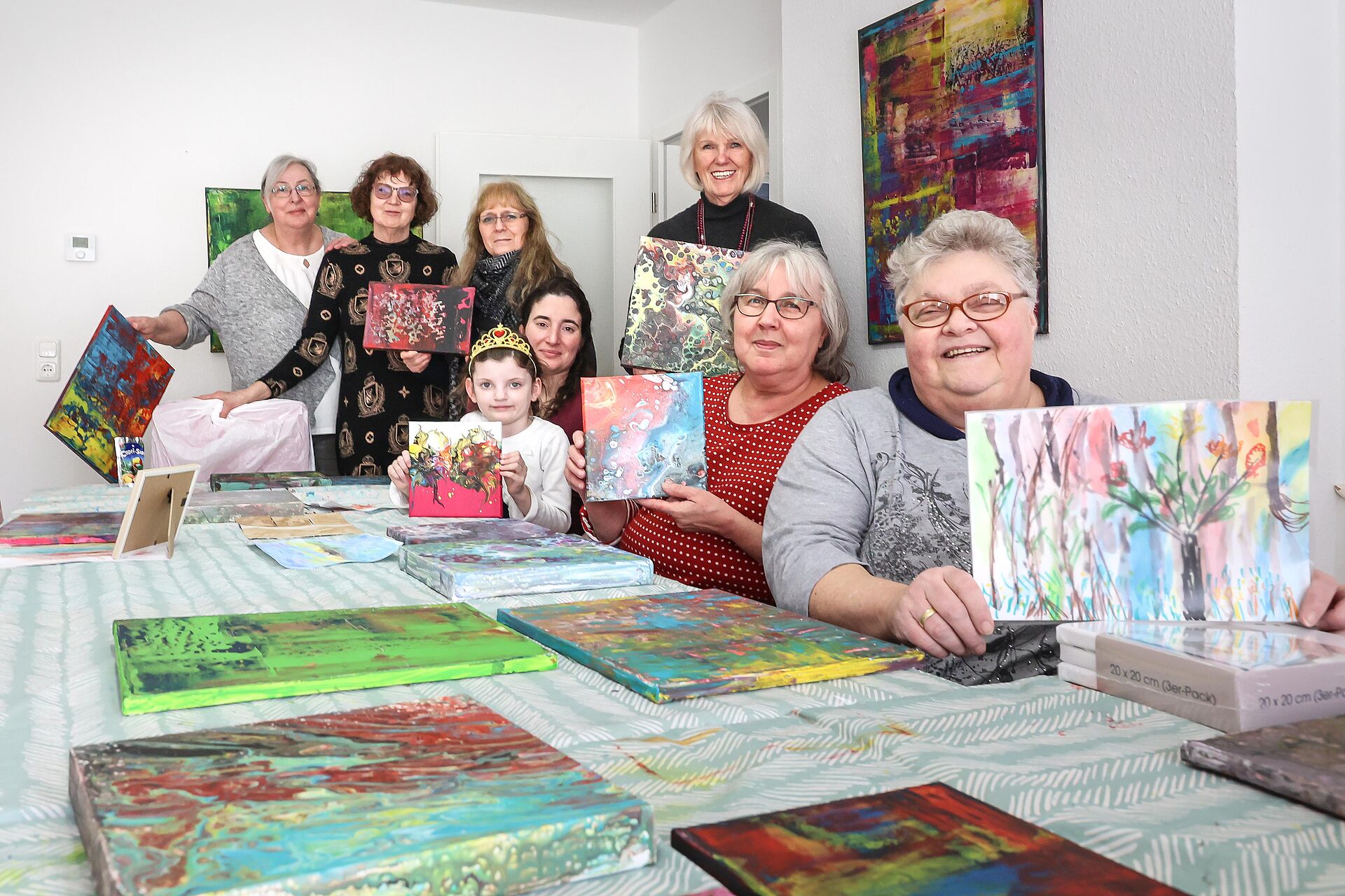 Mehrere Frauen sitzen an einem Tisch und zeigen ihre selbstgemalten Bilder