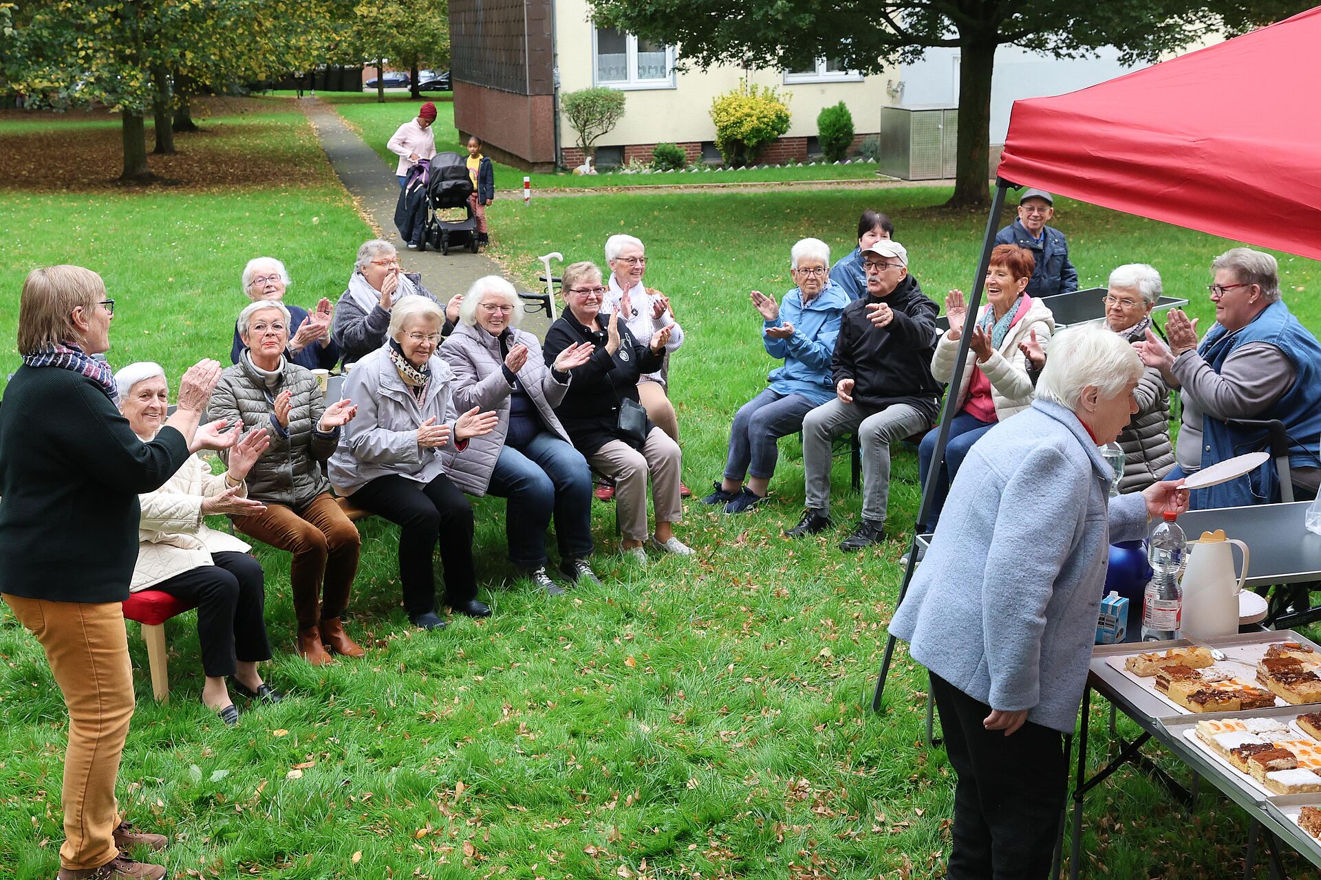 Menschen sitzen im Garten des Mietertreffs Kuh31 und haben Spaßchen